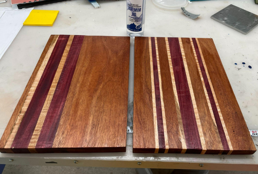 Two rectangular cutting boards with vertical stripes made of different kinds of wood.